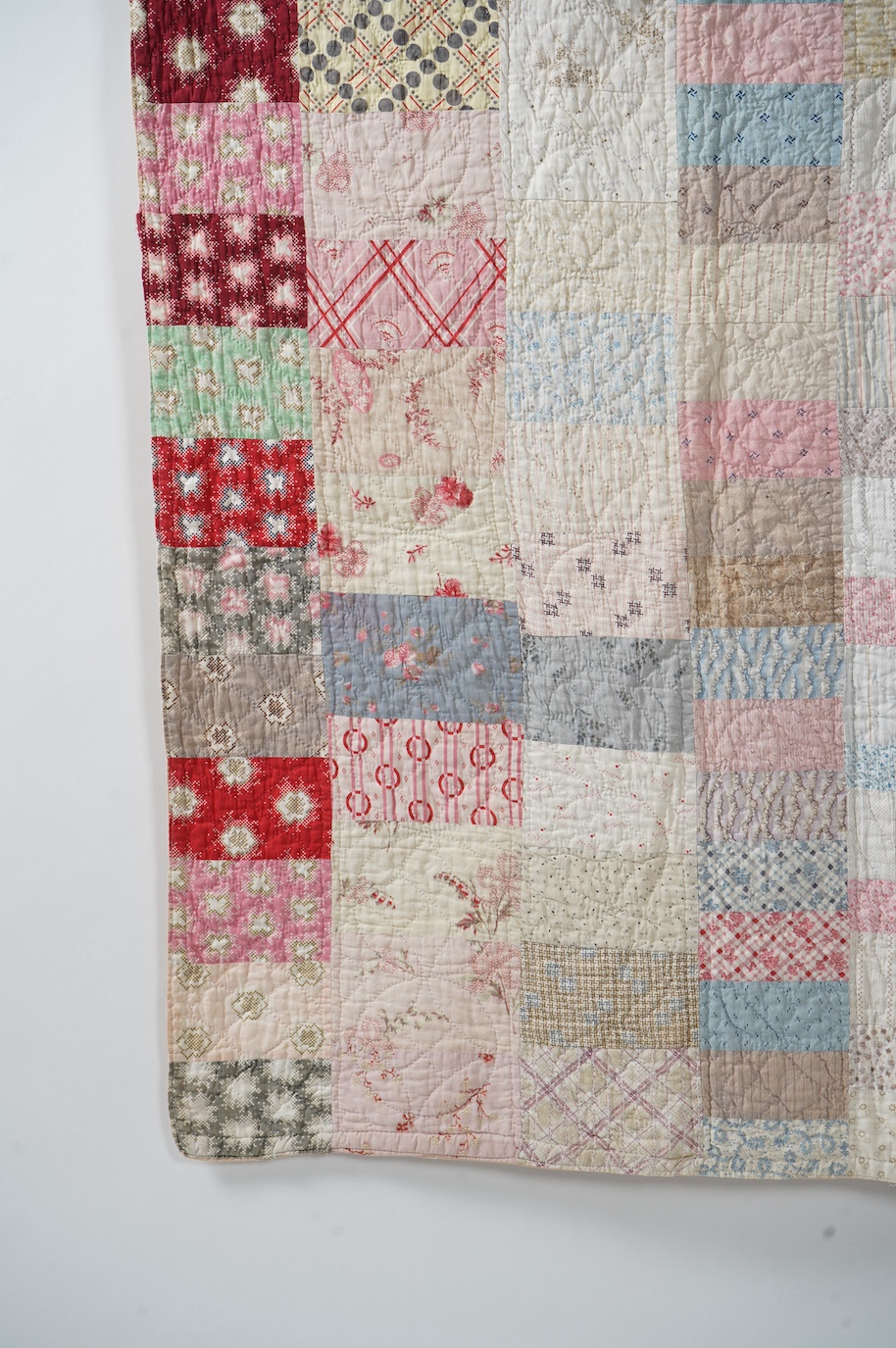 A late 19th early 20th century English cotton ‘scrap bag’ quilt., Made from a large variety of fashionable printed floral, striped and checked cottons of the day, cut into different sized rectangles and squares. Backed w